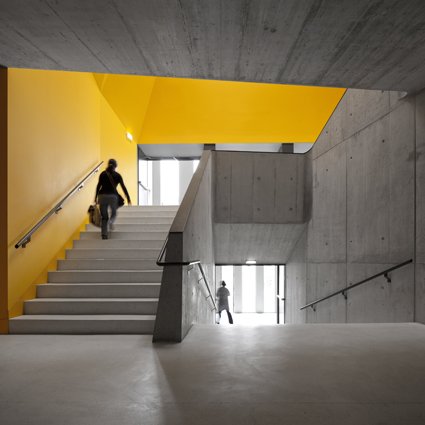 Vista escaleras de hormigón y techo con formas geométricas 3D en amarillo en Escola Braamcamp